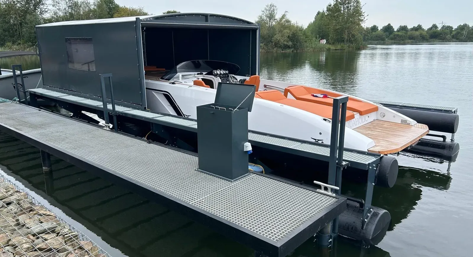 Motorboot op een drijvende bootlift met geopende bootoverkapping aan een meer